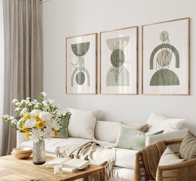 May include: Three framed abstract art prints with a minimalist design featuring green and beige geometric shapes and line drawings of leaves.