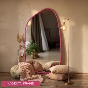 May include: A large, floor-standing mirror with an irregular, organic-shaped frame in a vibrant magenta color. The reflective surface shows a room interior, and the text "MAGENTA FRAME" is printed in white on a magenta rectangle at the bottom.