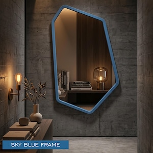 Peut inclure: Un miroir mural doté d'une forme géométrique irrégulière et d'un cadre bleu ciel lisse. La surface réfléchissante montre l'intérieur d'une pièce avec des livres et une lampe. Le texte "SKY BLUE FRAME" est imprimé dans un encadré bleu en bas.