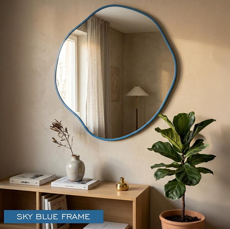 Peut inclure: Un miroir mural de forme organique irr&eacute;guli&egrave;re dot&eacute; d'un cadre bleu ciel lisse. La surface r&eacute;fl&eacute;chissante offre une vue claire d'un espace int&eacute;rieur, capturant la lumi&egrave;re et les environs dans son design de bordure unique et asym&eacute;trique.