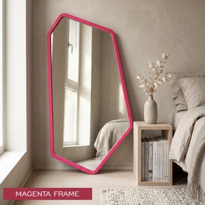 May include: A floor-standing mirror with an irregular, asymmetrical geometric shape and a solid magenta frame. The reflective surface shows a room interior, and the text MAGENTA FRAME is displayed in a red box at the bottom of the image.