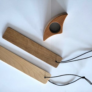 May include: Two wooden bookmarks with black string ties and a wooden page holder with a round hole in the center.