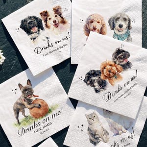 May include: A collection of white square paper napkins featuring watercolor illustrations of various dogs and a cat. Each napkin includes printed text such as Drinks on us, Drinks on me, or Cheers to forever, along with names and dates.