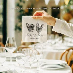 May include: A white square paper napkin featuring a black and white illustration of two French Bulldogs, the text "Tastes Like More" in a cursive script, and the printed names "Love, Duke & Delilah" with small heart icons on the sides.