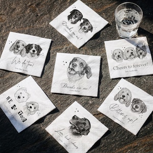 May include: Six square white paper napkins featuring black and white pencil-style illustrations of dogs. Each napkin displays unique text such as Drinks on me!, We do too!, and Cheers to forever!, along with personalized names and small heart icons.