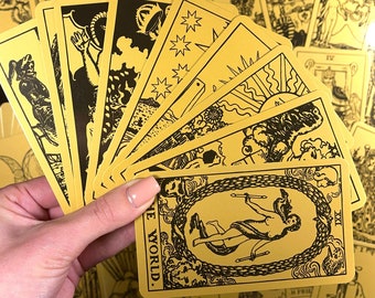 May include: A deck of tarot cards with gold and black illustrations. The cards are fanned out, with the "The World" card prominently displayed. Other cards show various figures and symbols. The overall theme is mystical and esoteric.