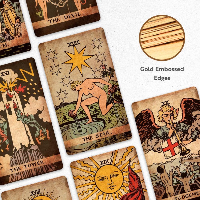 May include: A collection of vintage-style tarot cards with gold embossed edges. The cards feature illustrations and text, including "THE STAR," "THE DEVIL," and "THE TOWER." The artwork has a distressed, aged appearance.