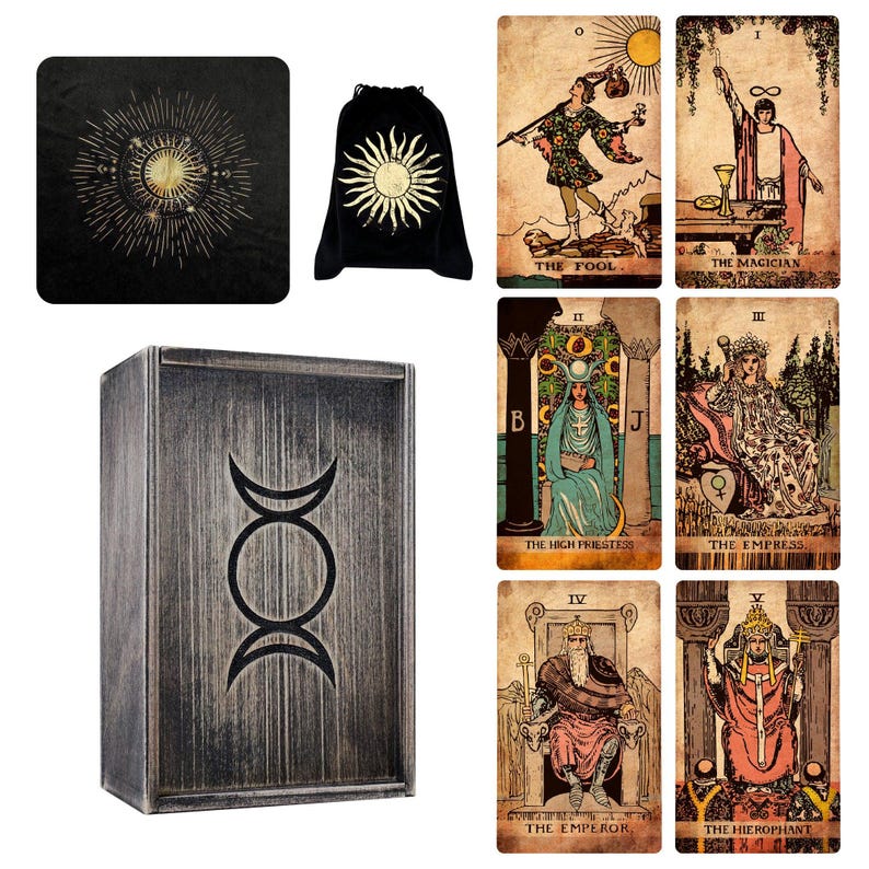 May include: A collection of tarot cards, a black velvet bag with a sun design, a black square mat with a sun design, and a wooden box with a triple moon symbol. The tarot cards feature illustrations and titles.