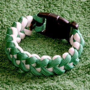 May include: A green and white paracord bracelet with a black plastic clasp.