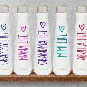 K&ouml;nnte beinhalten: F&uuml;nf wei&szlig;e Wasserflaschen mit unterschiedlich farbigem Text und Herzen. Der Text auf den Flaschen lautet "Grammy Life", "Nana Life", "Grandma Life", "Mimi Life" und "Abuela Life".