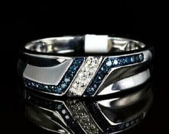 May include: A silver-toned ring with a geometric design. The ring features a central band of white stones flanked by bands of blue stones. The ring's design includes angled sections and a polished finish, reflecting light.