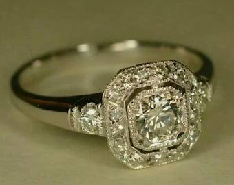 Peut inclure: Une bague de fiançailles en argent avec un grand diamant rond et clair entouré de diamants plus petits. La bague a un design délicat et complexe.