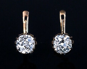 May include: A pair of gold earrings with a single round diamond in each earring.