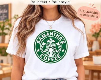 May include: A white short-sleeved t-shirt featuring a circular green graphic on the chest. The graphic depicts a stylized siren figure with the text SAMANTHA'S COFFEE printed in a circular border around the central icon.