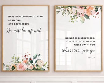 May include: Two framed wall art prints featuring floral arrangements in shades of pink, peach, and green. The left print reads: Have I not commanded you? Be strong and courageous. Do not be afraid. The right print reads: Do not be discouraged, for the Lord your God will be with you wherever you go. Joshua 1:9.