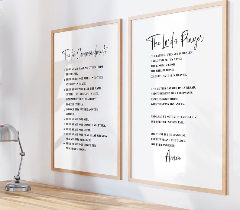 May include: Two framed prints with the text "The Ten Commandments" and "The Lord's Prayer" in elegant black script on a white background. The frames are light wood, and the prints are displayed on a wooden surface.