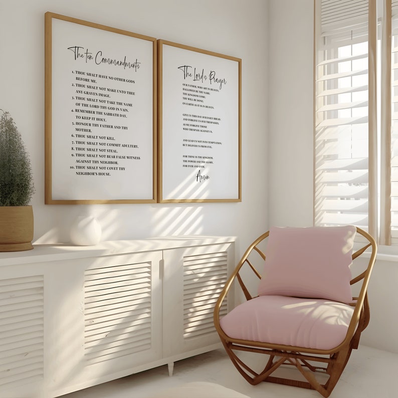 May include: Two framed prints on a white wall, one with "The Ten Commandments" and the other with "The Lord's Prayer" in black script. A light wood chair with a pink cushion sits nearby. A white cabinet and a potted plant are also in the room.