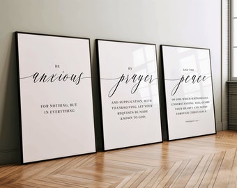 May include: Three black framed prints with white backgrounds and black calligraphy text. The first print says "Be anxious for nothing, but in everything". The second print says "By prayer and supplication, with thanksgiving, let your requests be made known to God". The third print says "And the peace of God, which surpasses all understanding, will guard your hearts and minds through Christ Jesus. Philippians 4:6-7"