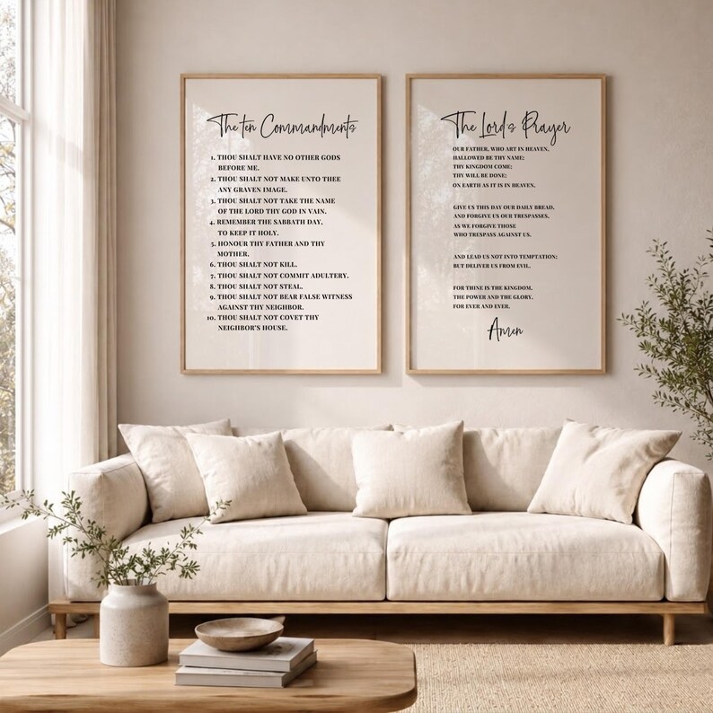 May include: Two framed art prints with the text of The Ten Commandments and The Lord's Prayer. The prints are in a light wood frame and hang above a beige sofa with matching pillows. A coffee table and vase are in front of the sofa.