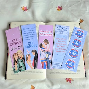 May include: Five rectangular bookmarks featuring illustrations of couples, hockey jerseys, and text including "Off Campus," "Mentally in Off-Campus," and "Malone's Guest Check." The bookmarks are displayed on an open book with a light fabric background.