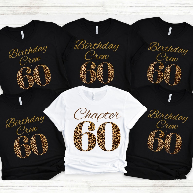 May include: Five t-shirts arranged in a group. Four black shirts feature the gold text Birthday Crew above a large leopard print number 60. One white shirt in the center features the brown text Chapter above a large leopard print number 60.