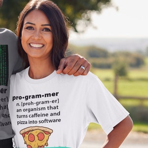 May include: A white t-shirt with a humorous definition of a programmer. The definition says a programmer is an organism that turns caffeine and pizza into software. The t-shirt is worn by a person with a green apron.