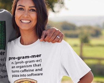 Pode incluir: Uma camiseta branca com uma definição humorística de um programador. A definição diz que um programador é um organismo que transforma cafeína e pizza em software. A camiseta é usada por uma pessoa com um avental verde.