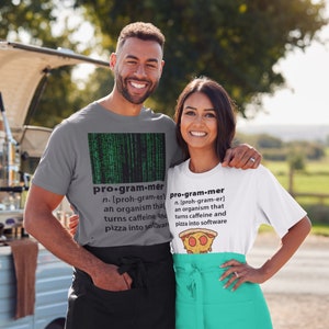 May include: Two people wearing grey and white t-shirts with a humorous definition of a programmer. The definition says a programmer is an organism that turns caffeine and pizza into software. The person wearing the grey shirt has a matrix-like green code pattern on their shirt. The person wearing the white shirt has a pizza graphic on their shirt.