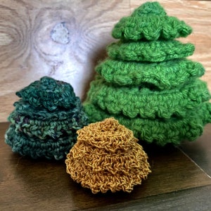May include: Three crocheted Christmas trees, one green, one green and blue, and one gold.