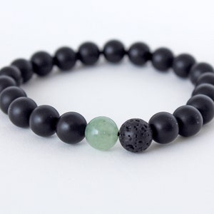 Peut inclure: Un bracelet en perles noires avec un accent de pierre verte et noire.