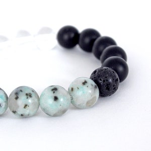 Peut inclure: Un bracelet composé de perles de lave noire, d'onyx noir et de jaspe vert et blanc.