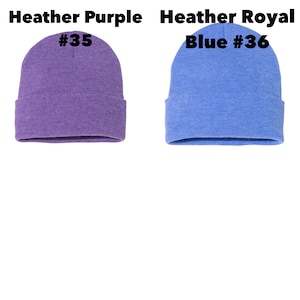 May include: Two cuffed knit beanies. The left beanie is heather purple and labeled Heather Purple #35. The right beanie is heather royal blue and labeled Heather Royal Blue #36. Both beanies feature a classic rounded crown and a folded cuff.