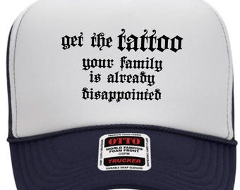 May include: A white and navy blue trucker hat featuring the black text "get the tattoo your family is already disappointed" in a gothic font. The hat includes a white foam front panel, a navy blue brim, and a rectangular product label.