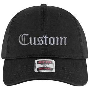 May include: Black dad hat with the word "Custom" embroidered in white script. The hat has a curved brim and a fabric strap closure. A white and black tag is attached to the brim.