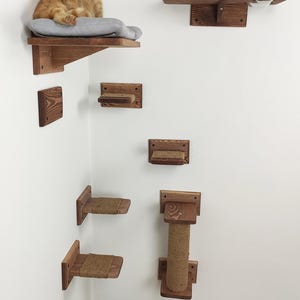 May include: A wooden cat tree with multiple platforms and a scratching post. The platforms are attached to the wall and are made of natural wood. The scratching post is covered in sisal rope. A cat is sitting on one of the platforms.