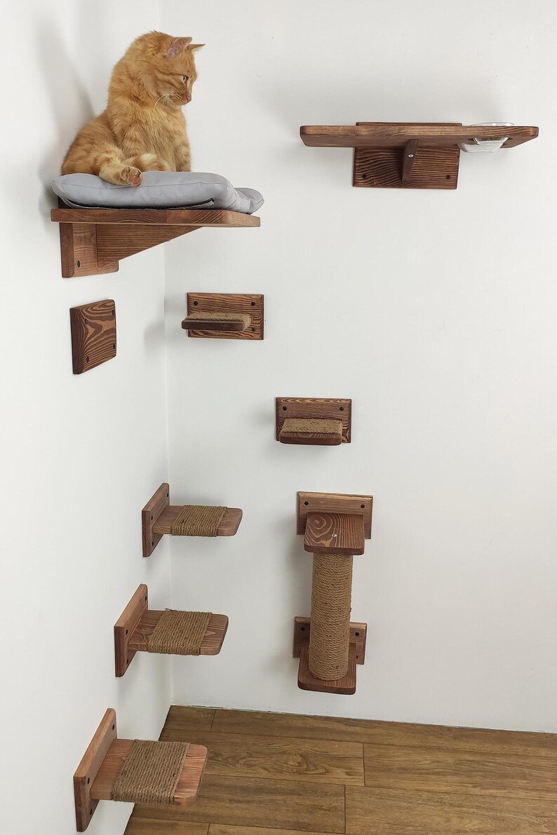 May include: A wooden cat tree with multiple platforms and a scratching post. The platforms are attached to the wall and are made of natural wood. The scratching post is covered in sisal rope. A cat is sitting on one of the platforms.