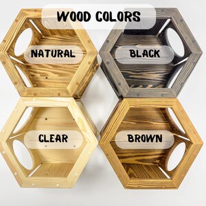 May include: Four hexagonal wooden cat beds in different wood finishes: natural, black, clear, and brown. The beds have a round opening on each side. The text "WOOD COLORS" is at the top of the image.