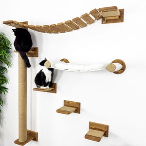 May include: A wooden cat tree with a hanging bridge, a hammock, and multiple platforms. Two cats are on the tree, one black and one black and white.