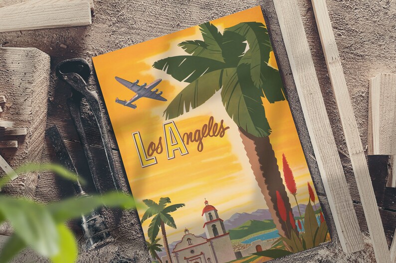 Puede incluir: P&oacute;ster de viaje vintage con fondo amarillo que presenta una palmera, una iglesia y un avi&oacute;n volando por encima. El texto "Los Angeles" est&aacute; escrito en una fuente estilizada.