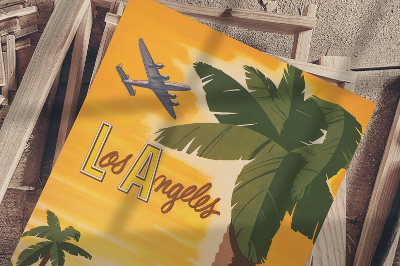 Puede incluir: Un cartel de viaje vintage con fondo amarillo que presenta una palmera y un avi&oacute;n volando sobre una puesta de sol. El texto "Los Angeles" est&aacute; escrito en una fuente retro.