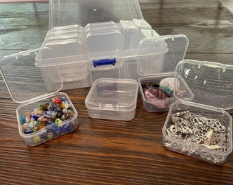 May include: A set of clear plastic storage containers with lids. The containers are various sizes and are filled with small items, such as beads, jewelry, and other craft supplies.
