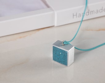 Smyckeshalsband med betonghänge och aluminiumkvadrater, perfekt som mors dag-present. Unika designersmycken i cement, lättviktigt