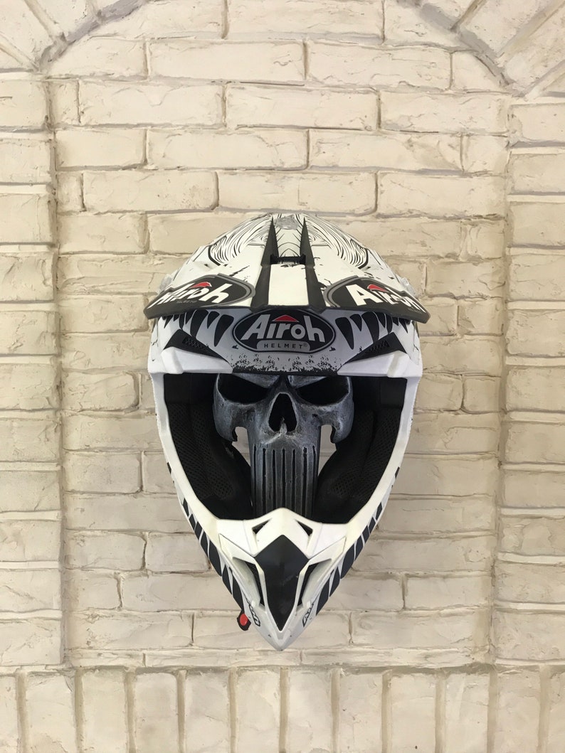 May include: White motorcycle helmet with a black and white skull graphic and the text "Airoh Helmet" on the side.