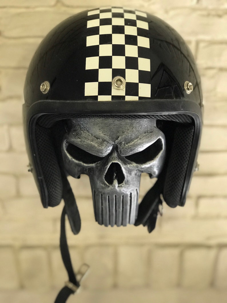 May include: Black motorcycle helmet with a chequered pattern on the top and a silver skull design on the inside.
