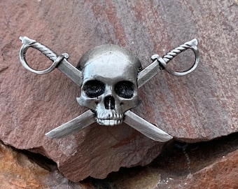 May include: A silver skull with crossed swords, a pirate-themed design.