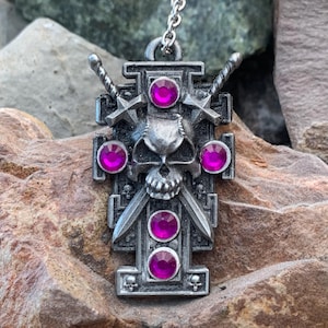 May include: A silver pendant necklace featuring a skull with crossed swords and five pink rhinestones.