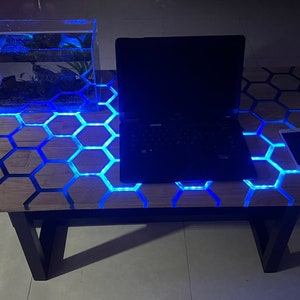 May include: A wooden table with a honeycomb design and blue LED lights. A laptop, a fish tank, and a cell phone are on the table. The table is made by TV WOOD RE-JIN.