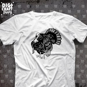 May include: A white t-shirt with a black silhouette of a turkey on the front. The turkey is facing to the left and has its wings spread out.