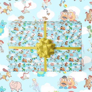 Puede incluir: Una caja de regalo envuelta con un fondo azul claro con un patr&oacute;n de personajes de Toy Story. La caja est&aacute; atada con una cinta dorada y un gran lazo dorado. Los personajes incluyen a Woody, Buzz Lightyear y Mr. Potato Head.