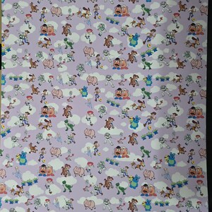 May include: A sheet of lavender-colored wrapping paper featuring a repeating pattern of cartoon characters, including a cowboy, a space ranger, a dinosaur, and a pig. White cloud shapes are interspersed throughout the design.